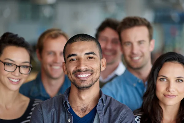 Jag känner mig stolt över våra prestationer. Skjuten av en leende grupp medarbetare som står på ett kontor. — Stockfoto