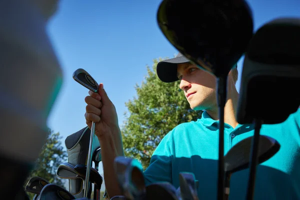 Utilisez toujours le bon outil pour le travail. Prise de vue d'un jeune homme concentré choisissant quel club de golf utiliser sur le terrain. — Photo