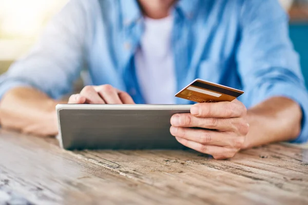 Bu aslında faturaları ödemenin daha kolay bir yolu. Tanınmayan bir adamın dijital tabletinden online alışveriş yaparken ve masada otururken kredi kartını tutarken görüntüsü.. — Stok fotoğraf