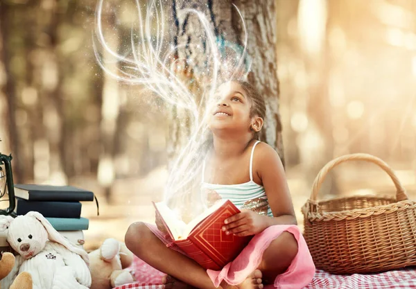 Öppna en bok och du öppnar ditt sinne. Skjuten av en liten flicka läser en bok med sina leksaker i skogen. — Stockfoto