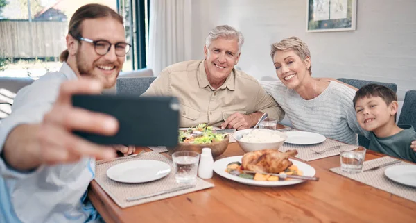 Величайшие воспоминания о жизни создаются между едой и семьей. Снимок семьи, делающей селфи во время ужина вместе дома. — стоковое фото