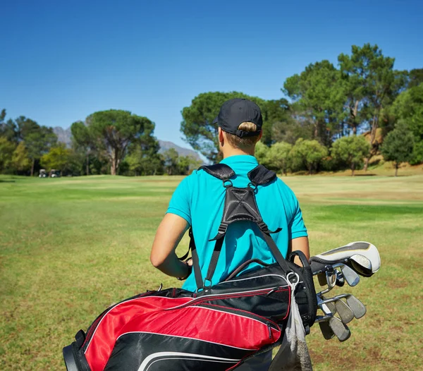 Aufgerüstet und bereit, Golf zu spielen. Aufnahme eines nicht erkennbaren jungen Mannes, der mit seiner Golfausrüstung draußen auf einem Golfplatz spaziert. — Stockfoto