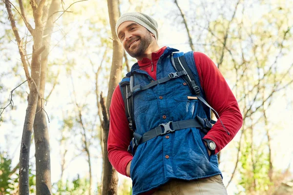 Nature is his happy place. Shot of a happy hiker out on a mountain hiking trail on his own. — Stock Photo, Image