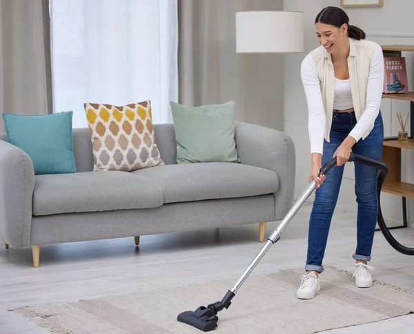 So many tiny crumbs. Shot of a young woman vacuuming the carpet in her home. — Stock Photo, Image