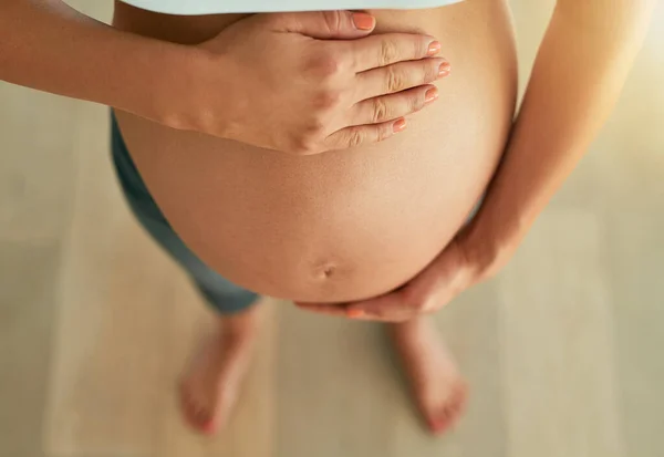 Ningún otro sentimiento se acerca. Cortado tiro de ángulo alto de una mujer embarazada sosteniendo su vientre desnudo. — Foto de Stock