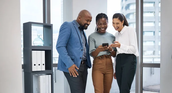 Partilhar uma ligação. Tiro de um grupo de empresários usando um celular juntos em um escritório. — Fotografia de Stock