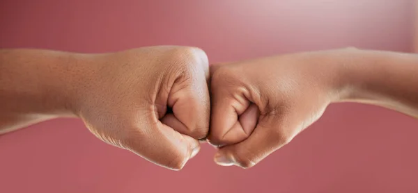 Einfach so. Schnappschuss zweier unkenntlich gemachter Personen, die im Studio vor rotem Hintergrund mit der Faust auf einen anderen einschlagen. — Stockfoto