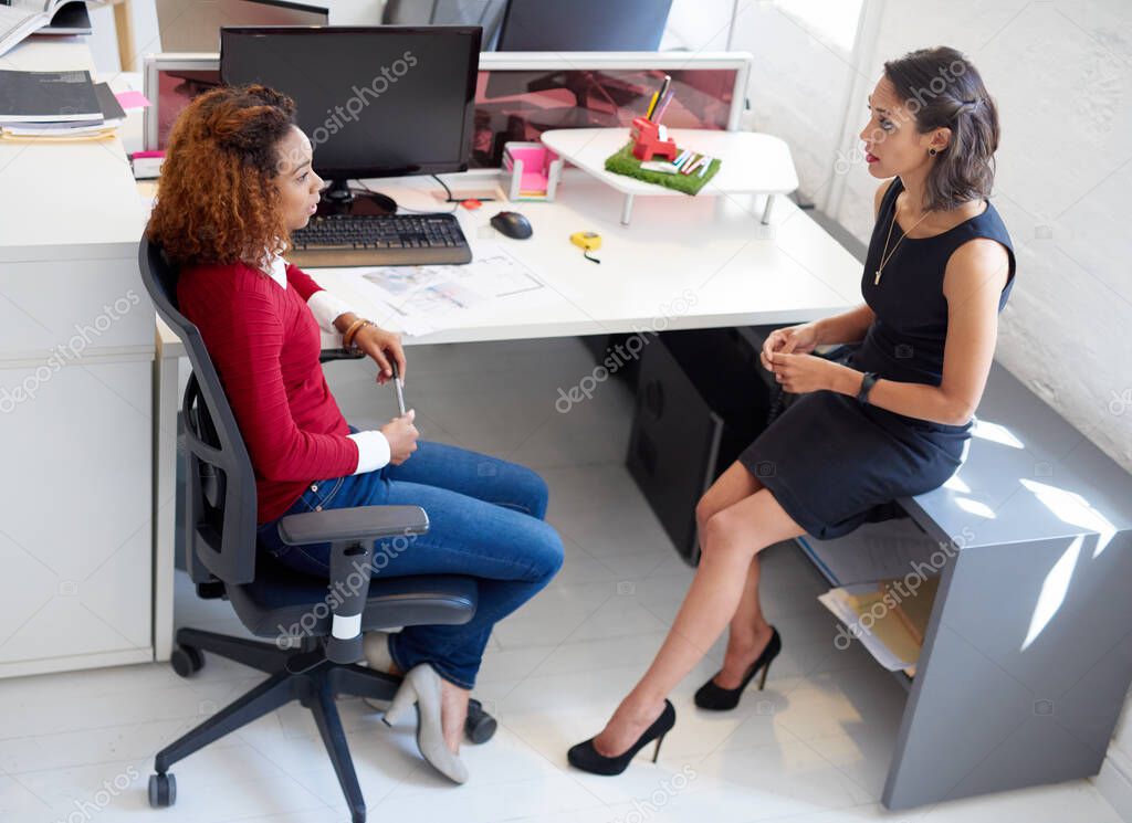 Theyre all about optimization. Shot of two female colleagues talking at a desk in an office.