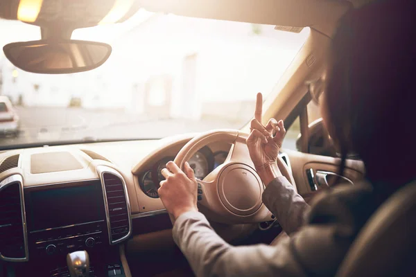 Hon tappade fattningen på vägen. Skjuten av en oidentifierbar affärskvinna som visar sitt långfinger när hon kör bil. — Stockfoto