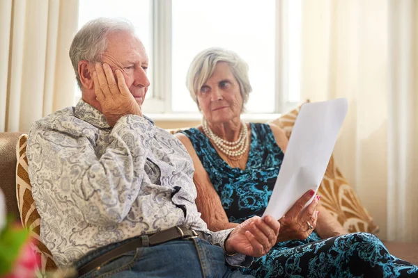 Less income, challenging outcomes. Shot of a senior couple going through their paperwork together at home and looking worried. — Foto de Stock