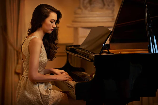 Det er bare henne og pianoet. Skutt av en vakker ung kvinne som spilte piano i et elegant rom. – stockfoto