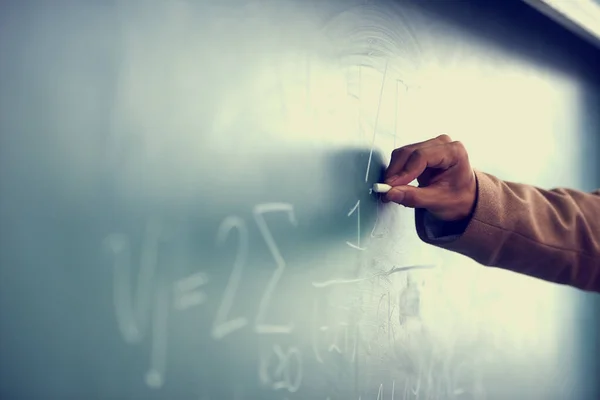 Its all greek to me. Cropped image of a teacher writing a formula on a blackboard. —  Fotos de Stock