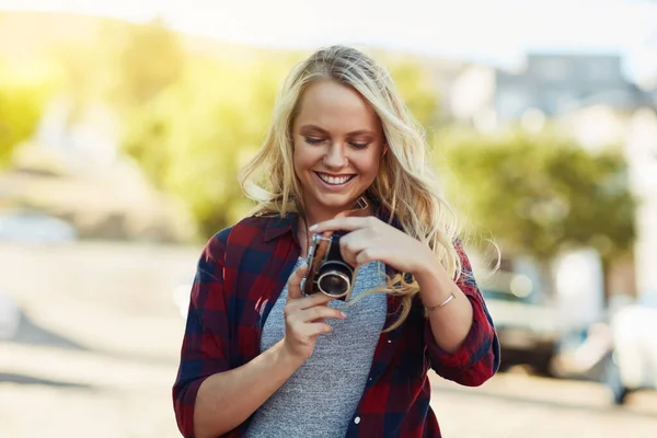 Die Fotos sehen tatsächlich fantastisch aus. Schnappschuss einer jungen schönen Frau beim Betrachten von Fotografien mit einer Kamera in der Stadt. — Stockfoto
