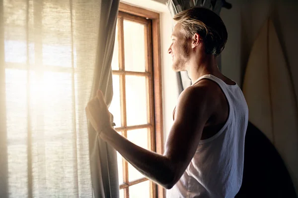 Gyönyörű napunk lesz ma. Vágott kép egy fiatalemberről, aki otthon néz ki az ablakon.. — Stock Fotó