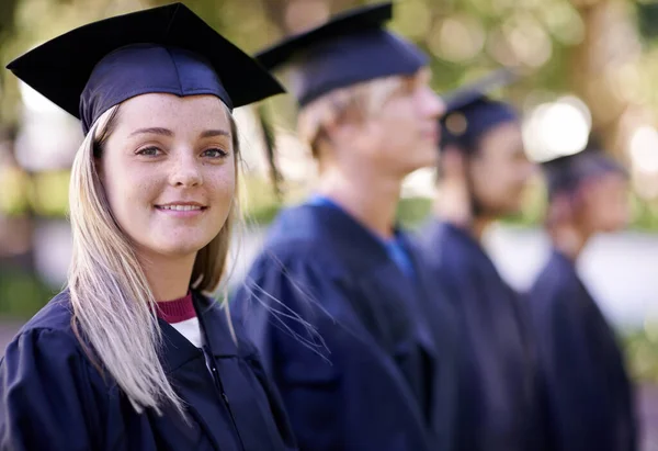 Garantir o futuro dela. Retrato de uma feliz pós-graduação em pé em uma fileira com seus pares à espera de seu diploma. — Fotografia de Stock