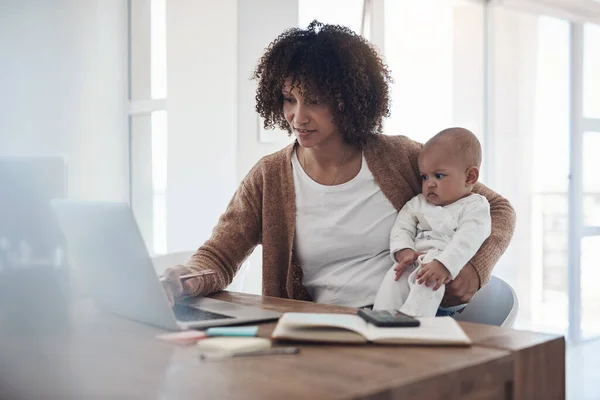 Se alguém consegue lidar com isso, a mãe consegue. Tiro de uma jovem mulher usando um laptop enquanto cuida de sua adorável menina em casa. — Fotografia de Stock