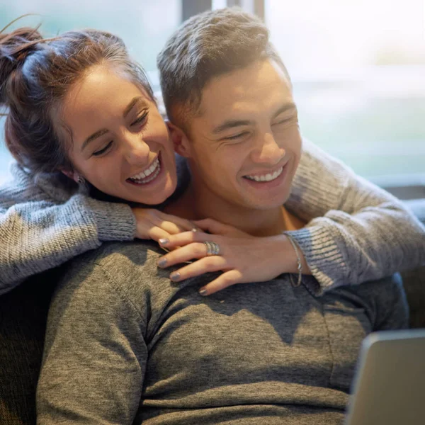 Sharing both love and laughter. Shot of an affectionate young couple surfing the net while relaxing on the sofa at home. —  Fotos de Stock