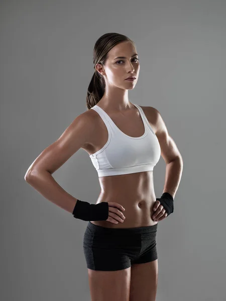 Sentirse fuerte por dentro y por fuera. Foto de una mujer atlética en ropa de entrenamiento de pie con las manos en las caderas. — Foto de Stock