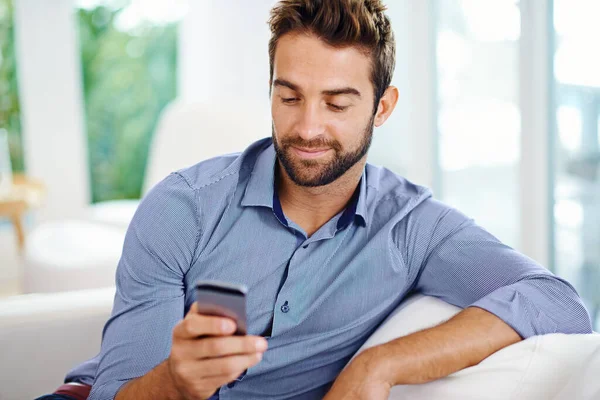 Tanta coisa pode fazer ao telefone hoje em dia. Homem usando seu celular em casa. — Fotografia de Stock