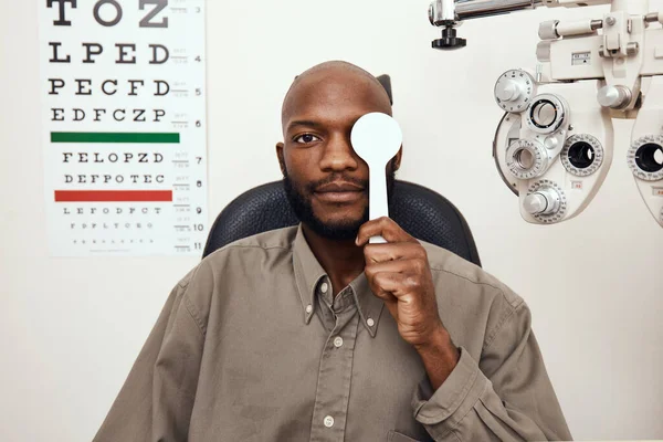 Faça um teste aos seus olhos para a saúde dele. Tiro de um jovem cobrindo o olho com um oclusor durante um exame oftalmológico. — Fotografia de Stock