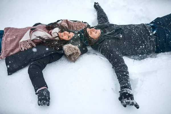 Der Schnee lässt uns wieder wie Kinder fühlen. Hochwinkelaufnahme eines im Schnee liegenden Paares, das Schneengel macht. — Stockfoto