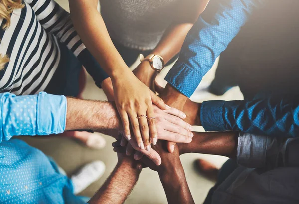 Fazê-lo através do trabalho em equipa. Tiro de um grupo de empresários criativos de pé com as mãos em um aconchego. — Fotografia de Stock