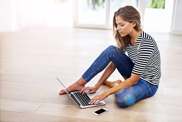 Shes a tech savvy surfer. Shot of a young woman sitting on the floor with her cellphone and laptop. — 스톡 사진