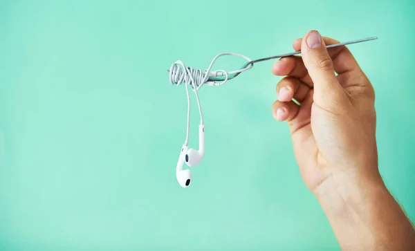 Serving up some soul food. Cropped studio shot of a man holding earphones wrapped around a fork against a turquoise background. — Foto de Stock