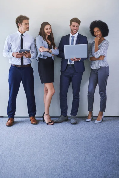 Mantenerse al día con los negocios en el espacio en línea. Fotografía de un grupo diverso de empresarios que utilizan la tecnología inalámbrica mientras están de pie sobre un fondo gris. — Foto de Stock