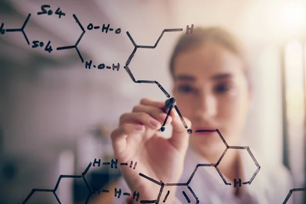 Jedna malá úprava. Snímek mladé vědkyně řešící rovnice na skleněné stěně v laboratoři. — Stock fotografie