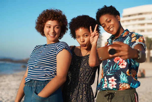 Doe alsof je dames bent. Opname van drie aantrekkelijke jonge vrouwen die op het strand liggen en overdag selfies samen nemen. — Stockfoto