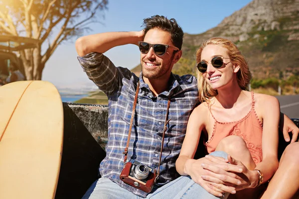 Something incredible could be right around the corner. Shot of a young couple relaxing on the back of a pickup truck while on a road trip. — 스톡 사진