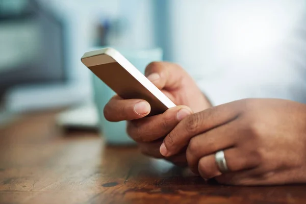 Sempre conectado, sempre disponível. close-up tiro de um homem de negócios mensagens de texto em um celular no trabalho. — Fotografia de Stock