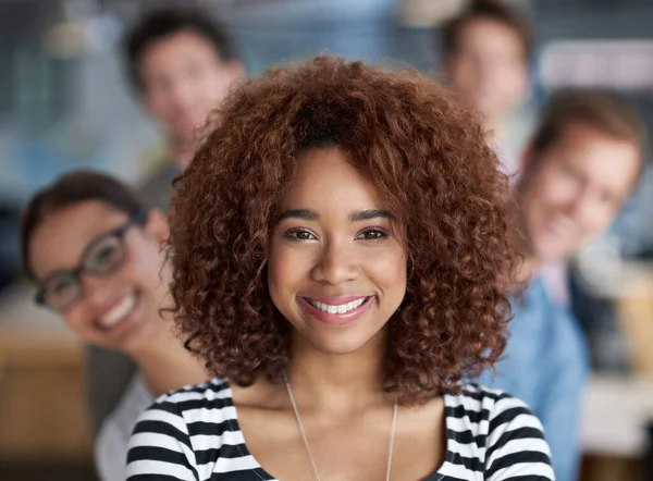 Tomando la iniciativa con confianza. Mujer joven sonriente mirando a la cámara con el personal en el fondo. — Foto de Stock