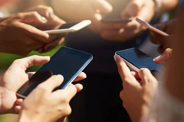 Sie alle haben viel zu sagen. Aufnahme einer Gruppe von Menschen, die ihre Mobiltelefone synchron im Freien benutzen. — Stockfoto