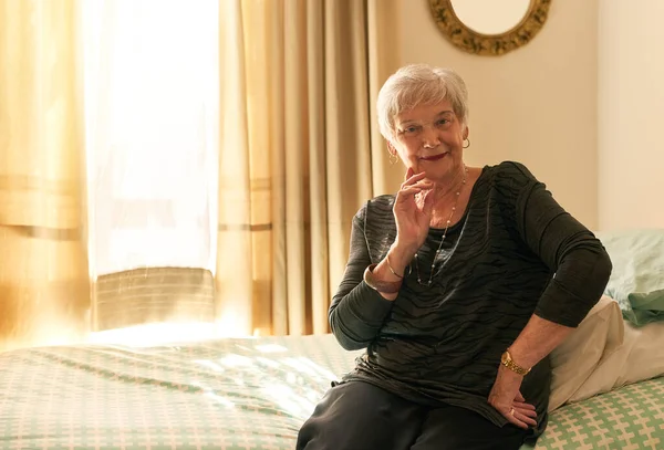 Ik heb een paar verhalen te vertellen. Portret van een tevreden oudere vrouw poseren in haar slaapkamer thuis. — Stockfoto