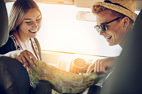 Es ist nicht mehr viel zu tun. Schnappschuss eines jungen Paares beim Lesen einer Landkarte während eines gemeinsamen Roadtrips. — Stockfoto