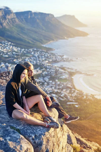 Godendo di una vista dall'alto. Colpo a figura intera di una giovane coppia seduta su una cima di montagna. — Foto Stock