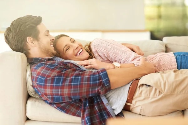Encajamos perfectamente. Foto de una feliz pareja joven relajándose en el sofá en casa. —  Fotos de Stock