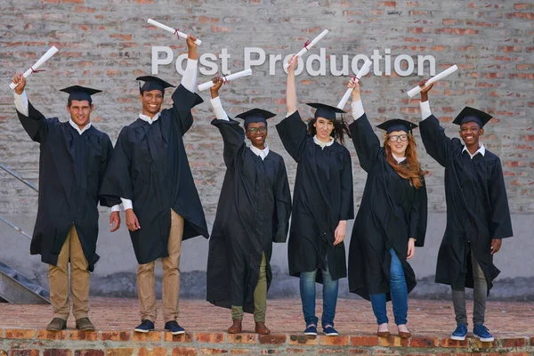 Ukończenie szkoły to dopiero początek. Portret szczęśliwej grupy studentów stojących ze swoimi dyplomami w dniu ukończenia szkoły. — Zdjęcie stockowe