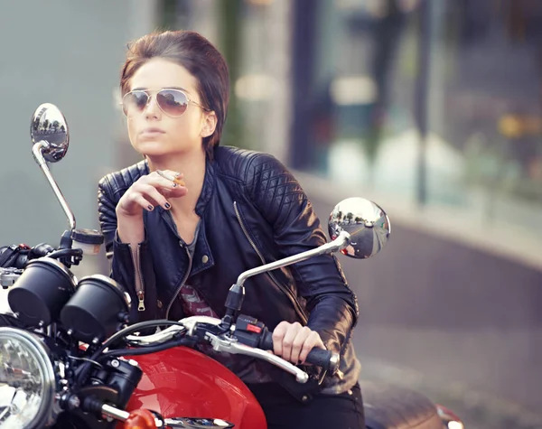 Shes an easy rider.... Shot of a young female biker smoking a cigarette. — Foto de Stock