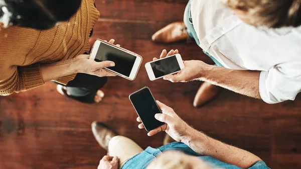 Colaborações conectadas. Foto de alto ângulo de um grupo de empresários irreconhecíveis usando seus celulares em sincronia em um escritório. — Fotografia de Stock