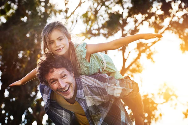 Ő egy vicces apa. Portré egy boldog apa és lánya élvezi a piggyback lovaglás szabadban. — Stock Fotó