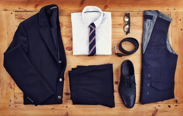 Stand out in the workplace with this stylish outfit. High angle shot of a stylish business outfit laid out on a wooden table. — Photo