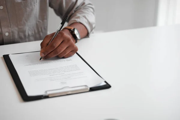 Signing his contract. High angle shot of an unrecognizable businessman filling out a form on a clipboard while sitting at his desk in the office. —  Fotos de Stock