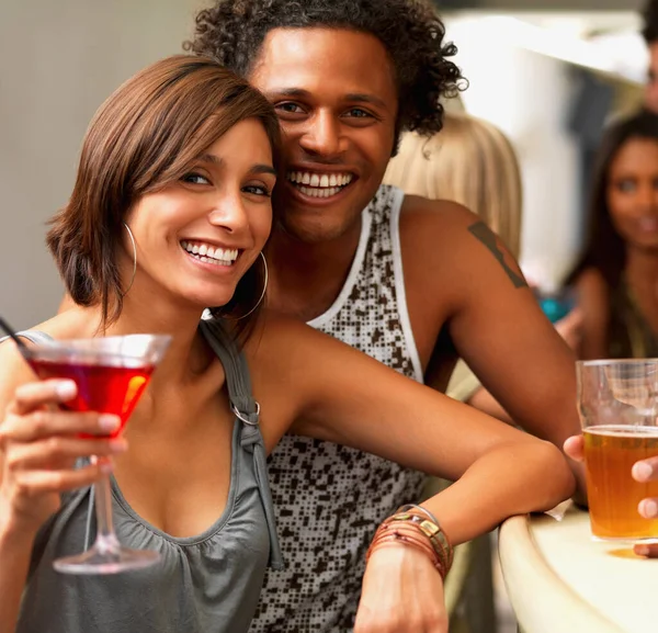 Fechar-se de um jovem casal sorridente num bar. Um retrato recortado de jovens felizes tomando bebidas em um bar. — Fotografia de Stock