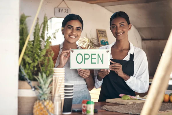 Venha apoiar novos negócios. Tiro de duas jovens empresárias segurando um sinal aberto em seu caminhão de comida. — Fotografia de Stock