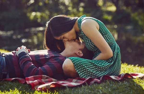 Inget säger romantik som en picknick i parken. Skjuten av ett kärleksfullt ungt par som kopplar av tillsammans på en picknickfilt i parken. — Stockfoto