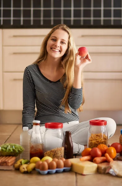 Healthy eating starts at home. Shot of an attractive young woman surrounded by various food in the kitchen at home. — 스톡 사진