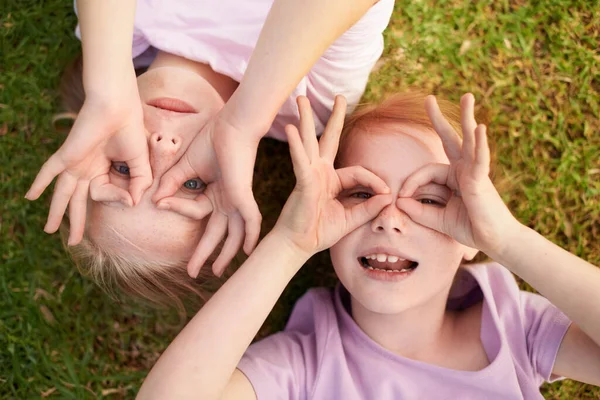우리는 볼 수있습니다. 등에 누워 있는 두 어린 소녀가 양손으로 눈 주위를 빙빙 돌고 있다. — 스톡 사진